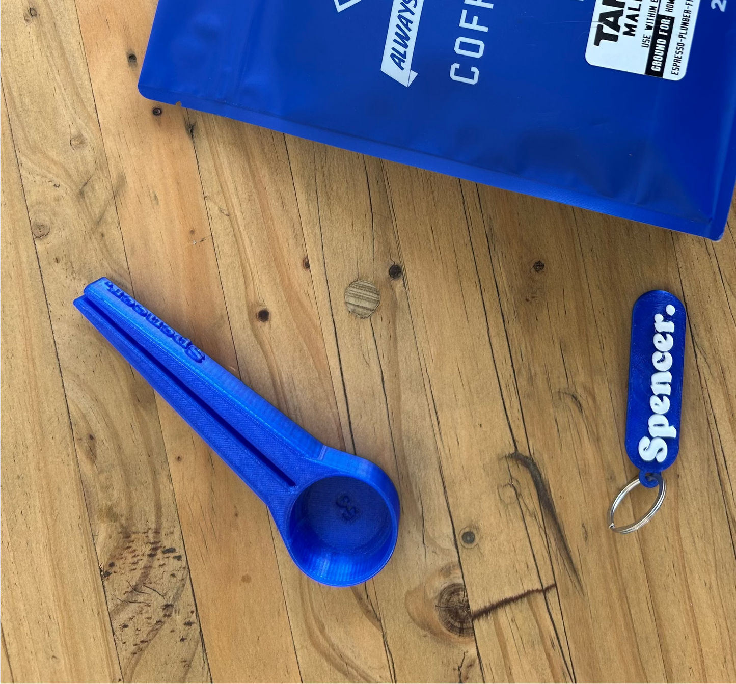 Blue coffee package with a spoon and keychain on a wooden surface